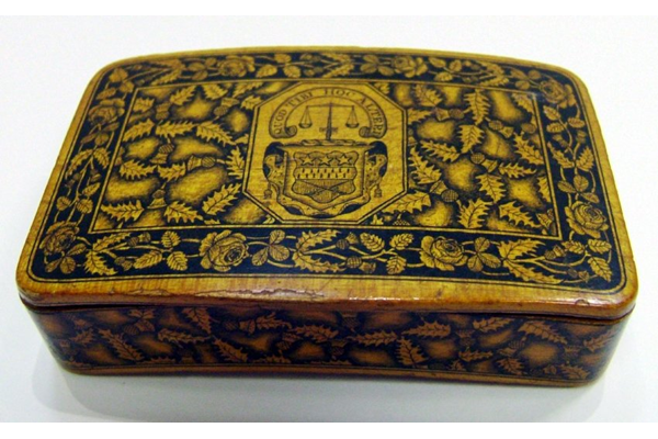 Small Mauchline ware wooden box decorated with a thistle design on all faces. In the centre of the lid is a coat of arms bearing the motto 'QUOD TIBI HOC ALTERI', motto of the Crawfurd of Cartsburn Family. - 1981.1104