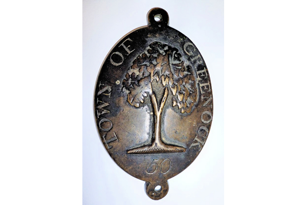 An official Burgh of Greenock Beggar's Badge, dated 1797-1803, issued to official beggar no.50. The badge is decorated with an image of an oak tree and inscribed 'Town of Greenock 50'. - 1977.284 - © McLean Museum and Art Gallery, Greenock