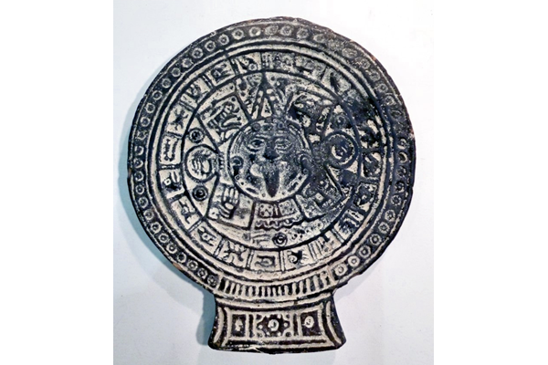 A black glazed flat ceramic zodiac disc from Mexico, period unknown, decorated with twenty signs in outer circle and four in the centre. - 1981.860 © McLean Museum and Art Gallery, Greenock.