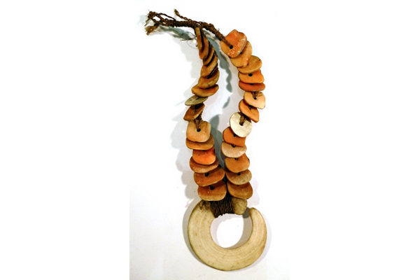 A late 19th century necklace from Papua New Guinea. The necklace is made of pink shell discs with large central white shell disc attached to a pig tusk. - 1981.491 © McLean Museum and Art Gallery, Greenock.