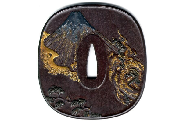 An early nineteenth century Japanese swordguard or tsuba. The design shows Mount Fuji and a storm dragon in relief and inlaid with gold and silver. Made by Sasagama Tokuhiro. - 1981.81 - © McLean Museum and Art Gallery, Greenock