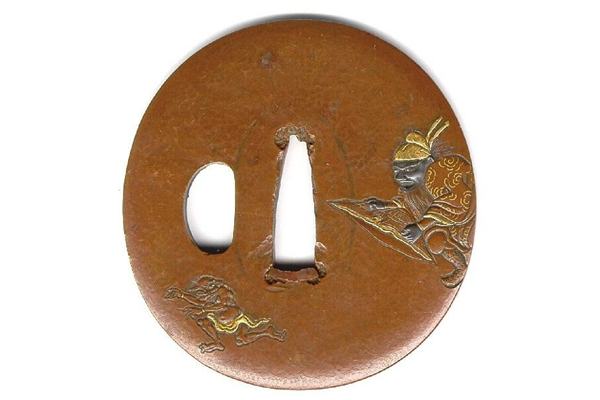 A eighteenth century Edo period Japanese swordguard or tsuba. The design shows Shoki the demon slayer pursuing a demon. Decorated with inlays and gilding. - 1981.150 - © McLean Museum and Art Gallery, Greenock