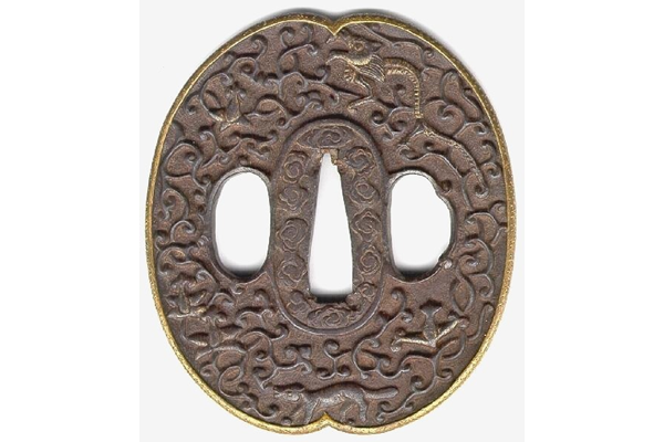 A Japanese swordguard or tsuba, date unknown. On both faces there is a floral design. One face shows an animal, possibly a dragon, and a fox. The edge of the tsuba is gilded. - 1981.158 - © McLean Museum and Art Gallery, Greenock