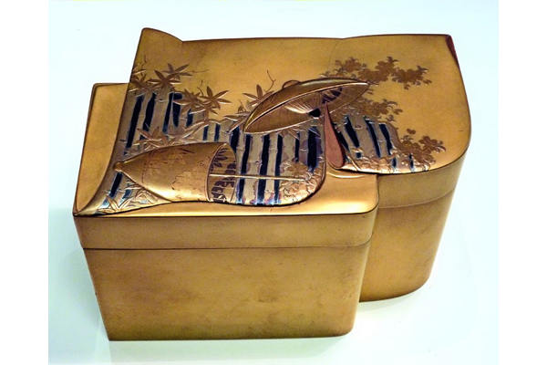 Japanese tea ceremony set box in lacquered wood. The box is in the form of a folded kimono decorated with a  fence with a parasol. The interior is in nashiji lacquer. - 1981.194 - © McLean Museum and Art Gallery, Greenock