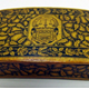 Small Mauchline ware wooden box decorated with a thistle design on all faces. In the centre of the lid is a coat of arms bearing the motto 'QUOD TIBI HOC ALTERI', motto of the Crawfurd of Cartsburn Family. - 1981.1104