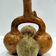 A ceramic stirrup pot, possibly made by the Chimú culture, from Peru, period unknown, coloured yellow/orange with a stirrup handle. The main pot is shaped as 4 fruits or gourds linked together. - 1981.847 © McLean Museum and Art Gallery, Greenock.